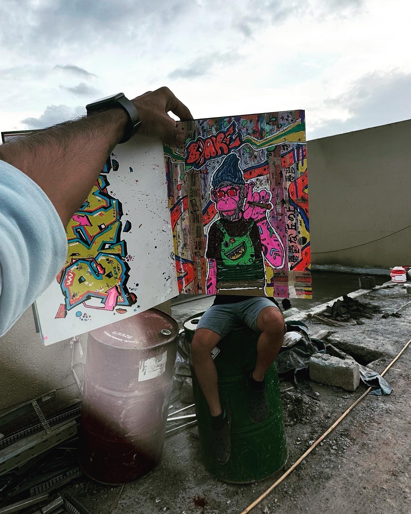A hand-painted artwork being held up on a rooftop
