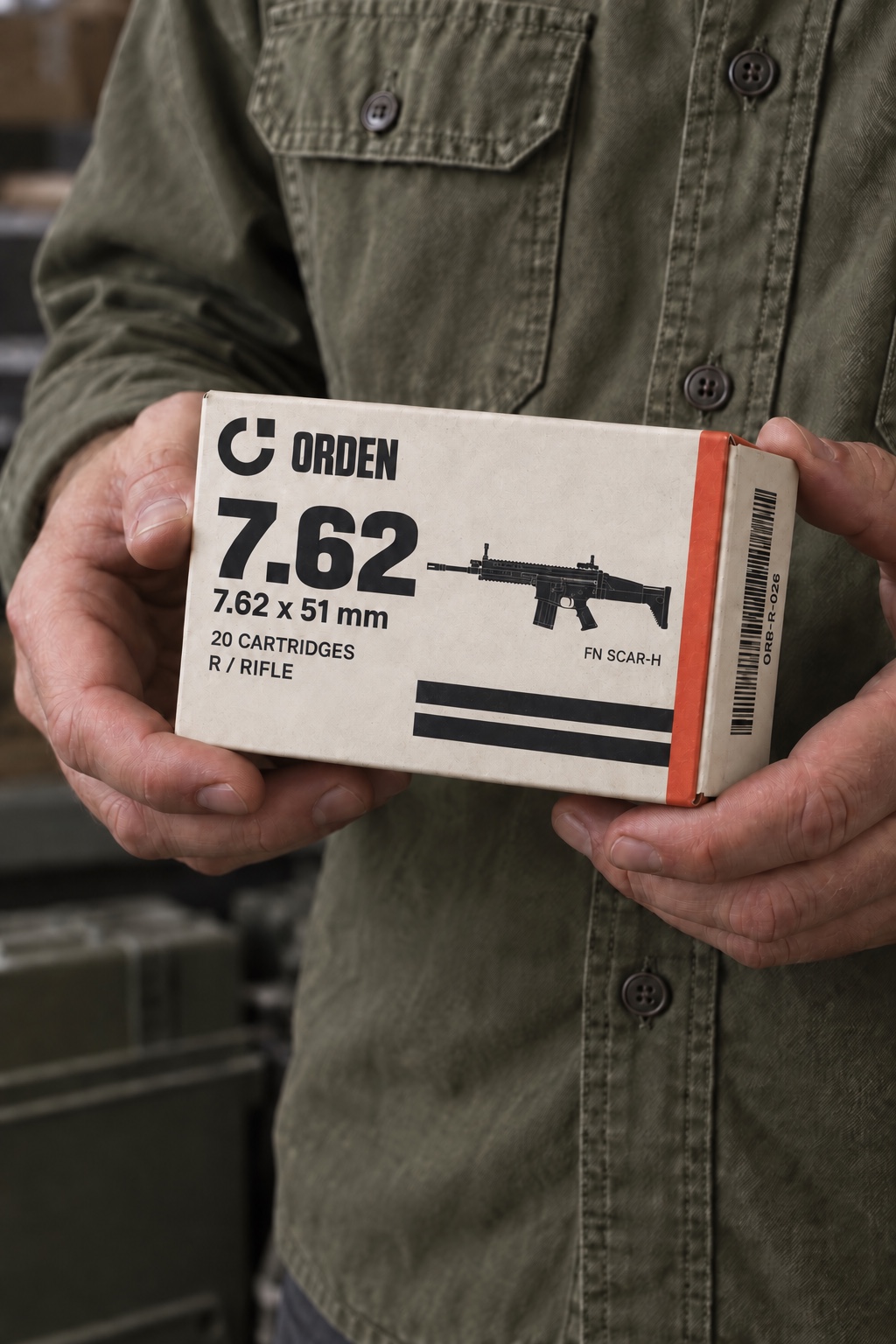 Hands holding a small ORDEN rifle carton against an olive work shirt.